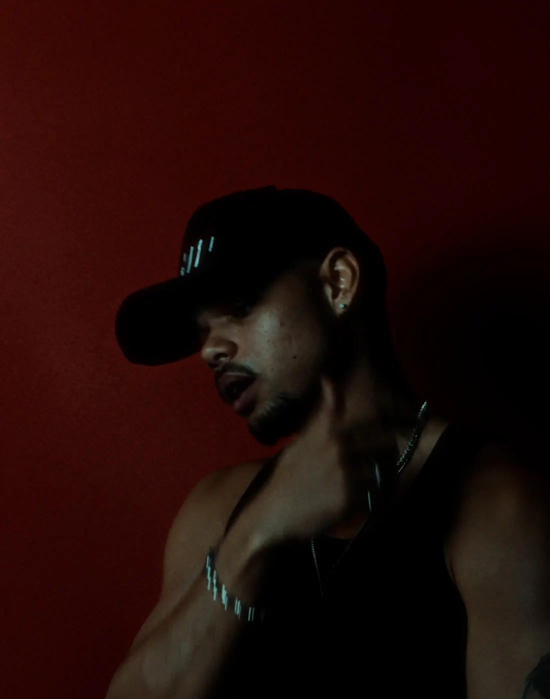 Ri-Flex under a single red light, hand at his neck